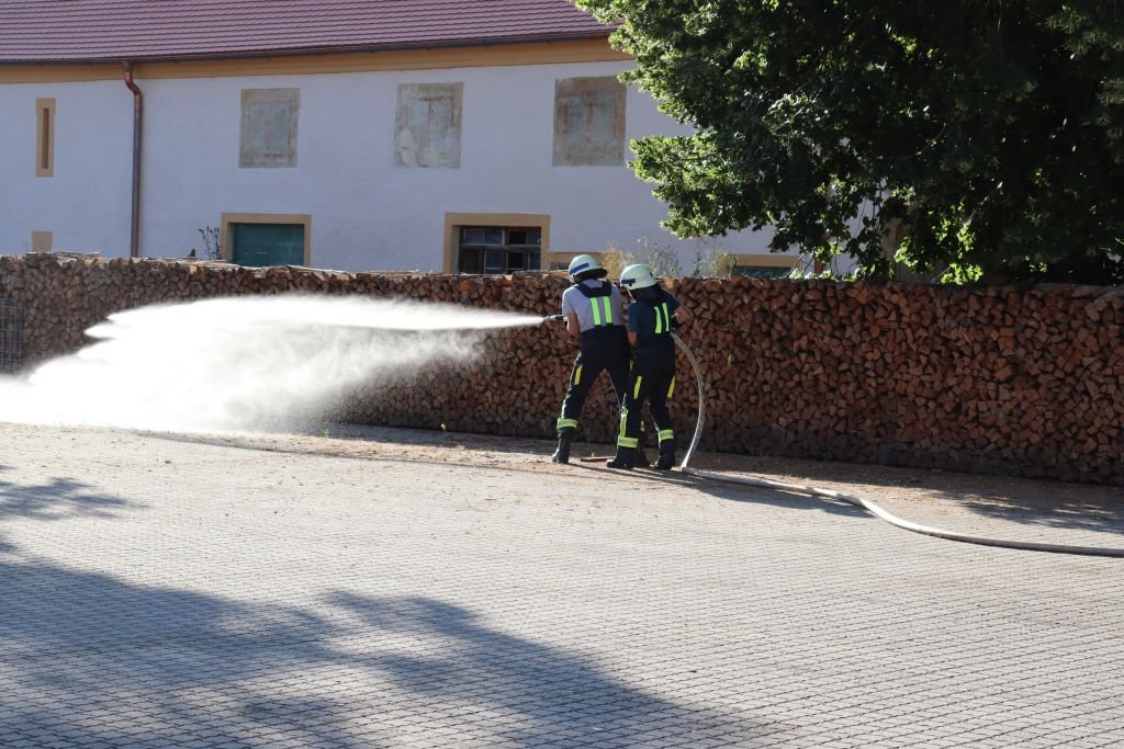Wassertrupp, spritzt mit dem zweiten Rohr den rechten Eimer um