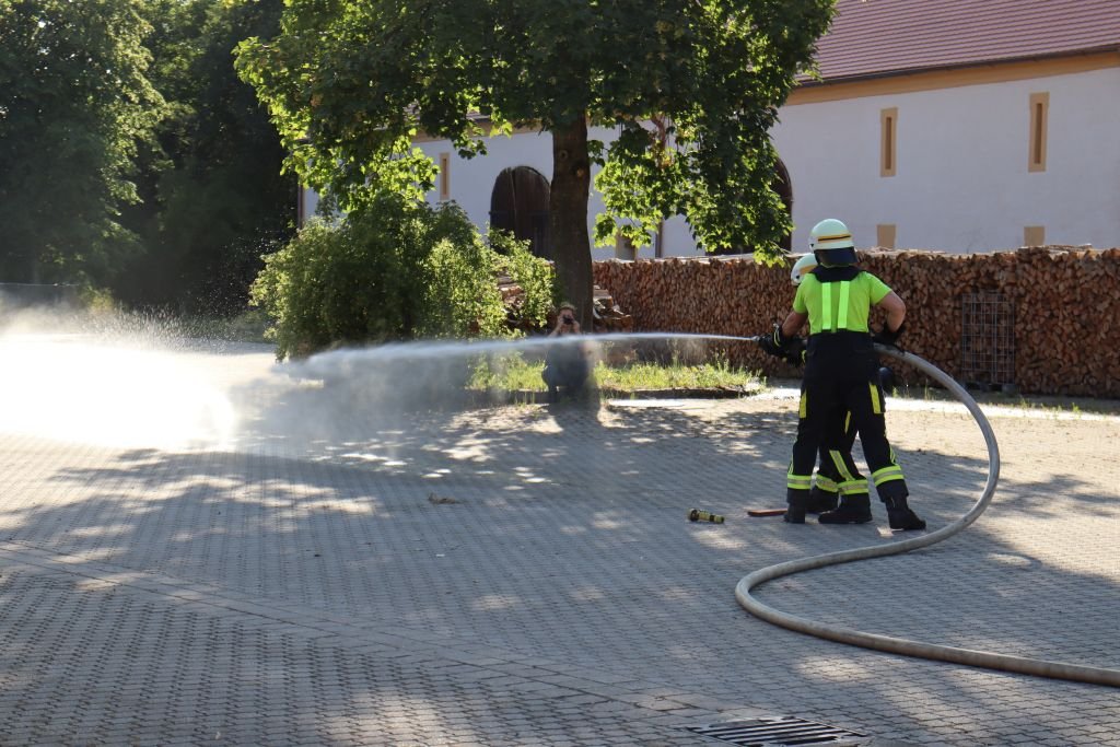 Schlauchtrupp spritzt mit dem dritten Rohr den mittleren Eimer um